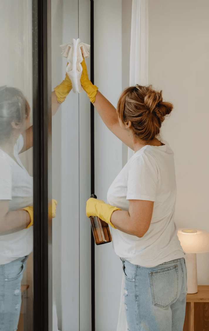 A cleaner in yellow gloves wiping down a doorframe